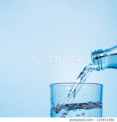Crystal clear water being poured into a transparent glass, creating refreshing ripples and bubbles Crystal clear water being poured into a transparent glass, creating refreshing ripples and bubbles 125651488