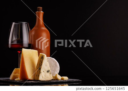 A refined selection of aged cheeses presented on a board, accompanied by a glasses of wine A refined selection of aged cheeses presented on a board, accompanied by a glasses of wine 125651645