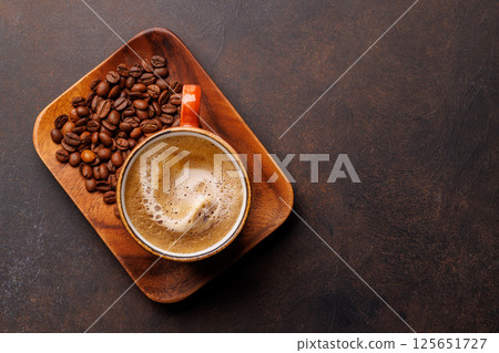 A steaming cup of freshly brewed coffee surrounded by rich, aromatic roasted coffee beans A steaming cup of freshly brewed coffee surrounded by rich, aromatic roasted coffee beans 125651727