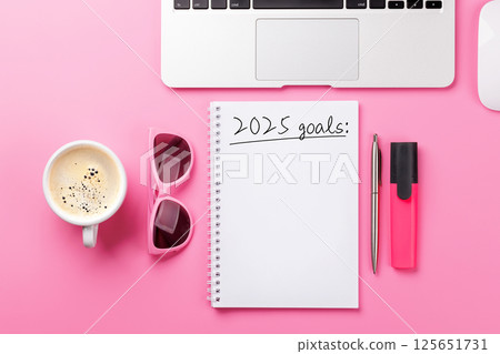 Modern pink desk with laptop, coffee, stationery, and a notepad titled 2025 Goals 125651731