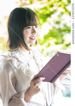 A young woman reading a book among the fresh greenery 125652070