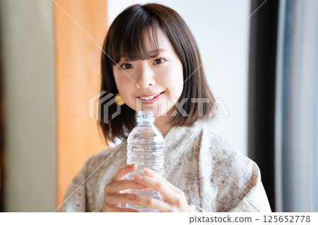 A young woman wearing a yukata hydrating 125652778