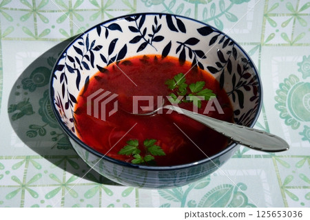 Discover the rich flavors of borscht, a traditional Ukrainian beetroot soup served in an ornate bowl with a touch of fresh herbs for a delightful touch 125653036