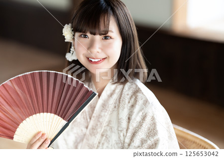 一位身穿浴衣的年輕女子拿著折扇乘涼 125653042