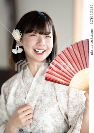 一位身穿浴衣的年輕女子拿著折扇乘涼 125653185