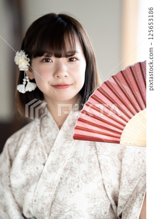 一位身穿浴衣的年輕女子拿著折扇乘涼 125653186