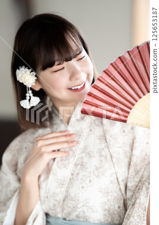一位身穿浴衣的年輕女子拿著折扇乘涼 125653187