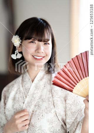 一位身穿浴衣的年輕女子拿著折扇乘涼 125653188