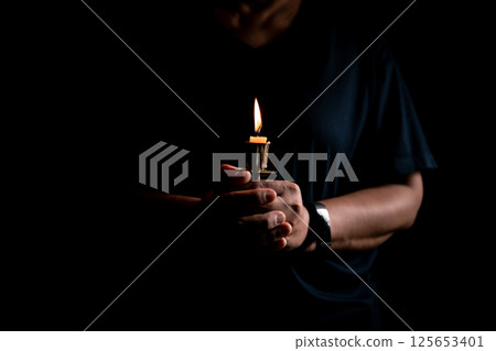 In the church, candle flickered beside cross as Christians gathered to pray, their faith in Jesus and spiritual devotion illuminated by Bible in background, deepening their Catholic worship. In the church, candle flickered beside cross as Christians gathered to pray, their faith in Jesus and spiritual devotion illuminated by Bible in background, deepening their Catholic worship. 125653401