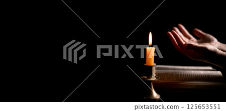 In the dark, hand clasped in prayer, illuminated by the soft candlelight, as black flames of candle fire flickered gently. candle, pray, hand, prayer, black, fire, flames, candlelight, light, dark. In the dark, hand clasped in prayer, illuminated by the soft candlelight, as black flames of candle fire flickered gently. candle, pray, hand, prayer, black, fire, flames, candlelight, light, dark. 125653551