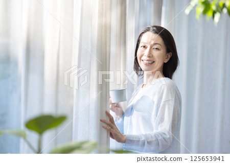 A woman drinking coffee at the window 125653941
