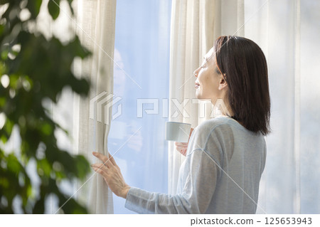 在窗口的婦女飲用的咖啡 在窗口的婦女飲用的咖啡 125653943