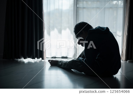 Silhouette of lost cast long shadow, embodying deep despair and hopelessness left him feeling perpetually stressed, sad, and unhappy. man sat alone, feeling weight of anxiety, stress, and depression. Silhouette of lost cast long shadow, embodying deep despair and hopelessness left him feeling perpetually stressed, sad, and unhappy. man sat alone, feeling weight of anxiety, stress, and depression. 125654066