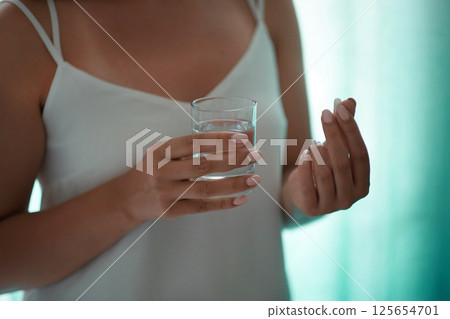 Sick female taking medicines, antidepressant, painkiller or antibiotic. Young lady drinking contraceptives. Pharmacy and healthcare concept 125654701