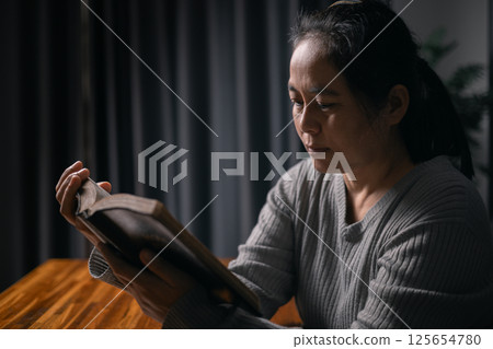 Woman bowed her head in prayer, her hand clasped in faith, as she prayed to Jesus Christ for hope, peace, and the guiding presence of God in her religion. god, religion, faith, hope, peace, christian. 125654780