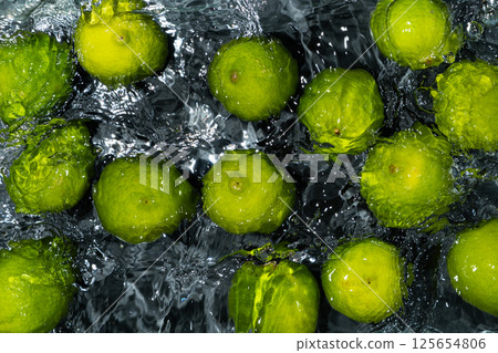 Whole Limes Drifting in Water with Soft Ripples 125654806