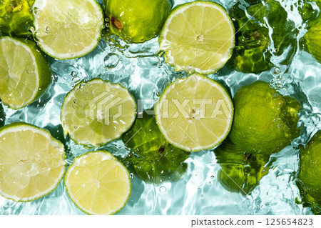 Bright fruity summer background of halves of fresh limes in water top view. Bright fruity summer background of halves of fresh limes in water top view. 125654823