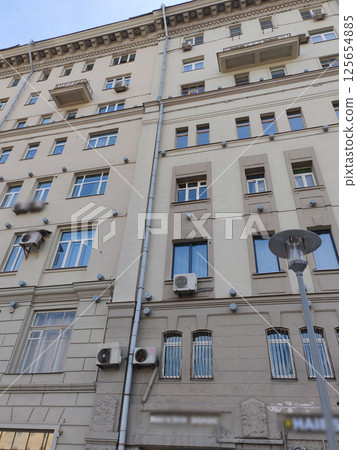 A modest gray building with stacked balconies, uniform windows, and visible air conditioning installations. This photo represents functional urban architecture balancing affordability and space A modest gray building with stacked balconies, uniform windows, and visible air conditioning installations. This photo represents functional urban architecture balancing affordability and space 125654885