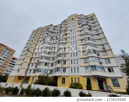 A pastel-colored high-rise residential building with curved balconies and windows, set above a courtyard. The architecture showcases modern urban development and the growing demand for multi-story A pastel-colored high-rise residential building with curved balconies and windows, set above a courtyard. The architecture showcases modern urban development and the growing demand for multi-story 125654886