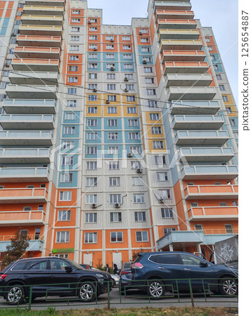 A towering residential building with pastel accents, featuring a wide array of windows and balconies. The design reflects the contemporary urban approach to high-density living in city environments. A towering residential building with pastel accents, featuring a wide array of windows and balconies. The design reflects the contemporary urban approach to high-density living in city environments. 125654887