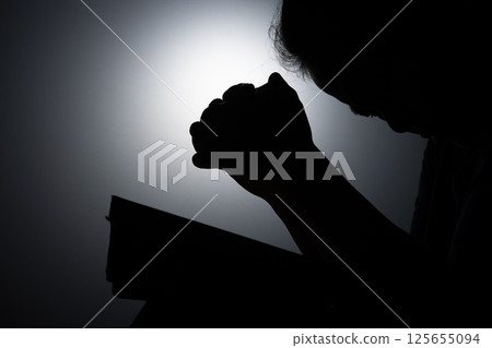 Profile silhouette of girl, young woman lowered her head and praying to God. Female catholic prayer worship to God wish a better life in home at dawn with believe faith. 125655094