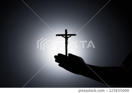 Praying hands holding a cross, Close up holding cross, pray for god in the dark, religious Christian symbol with copy space background. God and Spiritual Concepts. Praying hands holding a cross, Close up holding cross, pray for god in the dark, religious Christian symbol with copy space background. God and Spiritual Concepts. 125655099