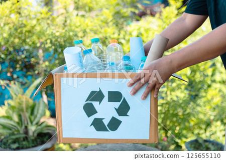 Plastic bottle waste for recycling, reuse concept. Volunteers store plastic bottles in cardboard boxes at a park. Disposal, recycling and waste management. Good conscience. 125655110