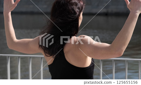 A woman with athletic shoulders and arms exercises outdoors, emphasizing physical strength. The scene conveys motivation, endurance, and an active lifestyle. 125655156