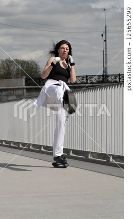A woman engages in an intense workout, kicking with precision while maintaining stability on jumping shoes. This image represents athleticism, focus, and modern fitness trends. 125655299