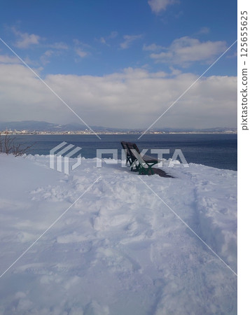 Looking out at the winter sea from a bench 125655625