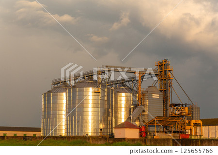 Group of grain dryers complex on dramatic cloudy sunset sky. Group of grain dryers complex on dramatic cloudy sunset sky. 125655766
