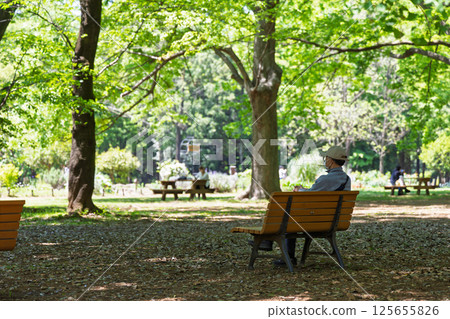 A middle-aged Japanese man sitting alone on a park bench A middle-aged Japanese man sitting alone on a park bench 125655826