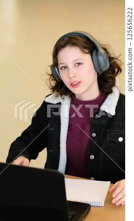 A young girl poses with her laptop in a professional setting, her expression calm and reflective. This image aligns with themes of authenticity, self-confidence, and the integration of technology in 125656222