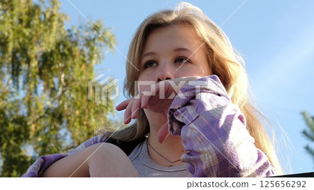 teenage girl with a tearful expression gazes into the distance, framed by vibrant greenery and soft sunlight. The photo captures raw emotions and a moment of quiet sadness. teenage girl with a tearful expression gazes into the distance, framed by vibrant greenery and soft sunlight. The photo captures raw emotions and a moment of quiet sadness. 125656292