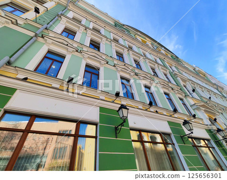 A historic building facade painted in green with white decorative columns and black lanterns. This scene highlights the preservation of traditional architecture in a modern cityscape. 125656301
