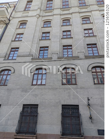 A striking urban canyon formed by tall, contrasting gray and red brick buildings under a clear sky. 125656320