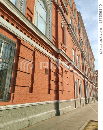 A row of secured windows with wrought-iron grilles against a vibrant red brick wall. The photo captures a balance of security, functionality, and aesthetic appeal. 125656340
