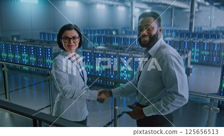 Big Data Center Multiethnic Specialists Talking, Shaking Hands, Looking at Camera Big Data Center Multiethnic Specialists Talking, Shaking Hands, Looking at Camera 125656513