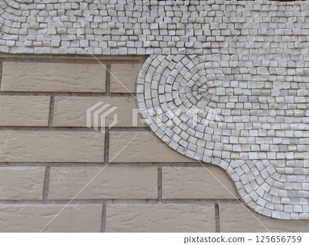 A minimalistic mosaic design featuring white tiles in a semi-circular pattern against a beige brick wall. The smooth gradient adds a modern, elegant touch. 125656759