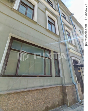 A worn facade of a historic building with rectangular windows and aged plaster. The image captures the character of urban decay and the need for restoration in historic districts. A worn facade of a historic building with rectangular windows and aged plaster. The image captures the character of urban decay and the need for restoration in historic districts. 125656774