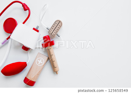Colorful wooden toy doctor kit with stethoscope and syringe on white background 125658549