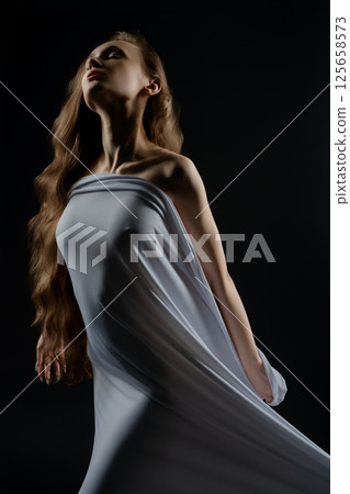 Woman poses confidently in flowing garment during casting session indoors 125658573