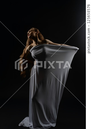 Model poses elegantly in flowing white dress during casting session at studio Model poses elegantly in flowing white dress during casting session at studio 125658576