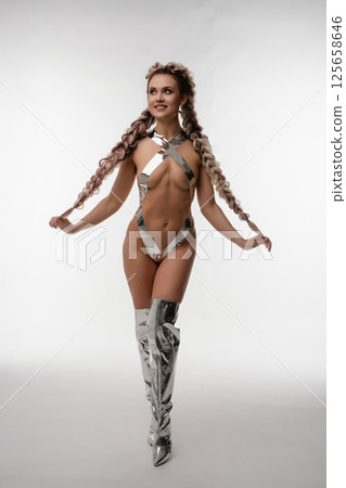 Woman in silver body art poses confidently in lingerie-inspired outfit 125658646