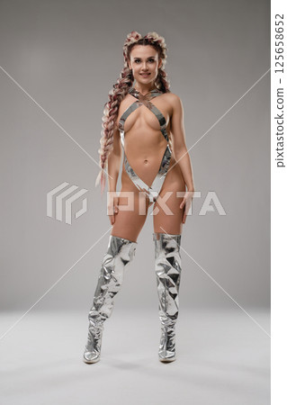 Bold bodyart display featuring a woman in silver tape and lingerie 125658652