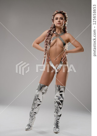 Woman in silver bodyart poses confidently in unique lingerie at a studio Woman in silver bodyart poses confidently in unique lingerie at a studio 125658653