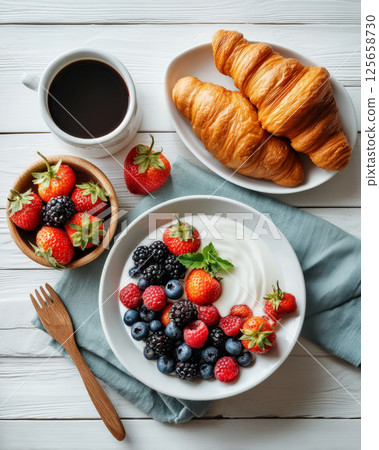 Healthy breakfast with croissant, berries, yogurt and coffee on white table 125658730