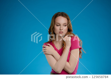 Woman poses with emotional expression in a studio setting against a vibrant blue background Woman poses with emotional expression in a studio setting against a vibrant blue background 125658784