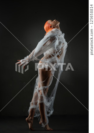 Red-haired woman entangled in a delicate web under soft lighting Red-haired woman entangled in a delicate web under soft lighting 125658814