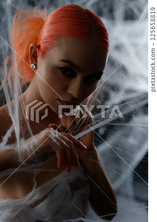 Red-haired woman entangled in a delicate web during a mysterious night Red-haired woman entangled in a delicate web during a mysterious night 125658819